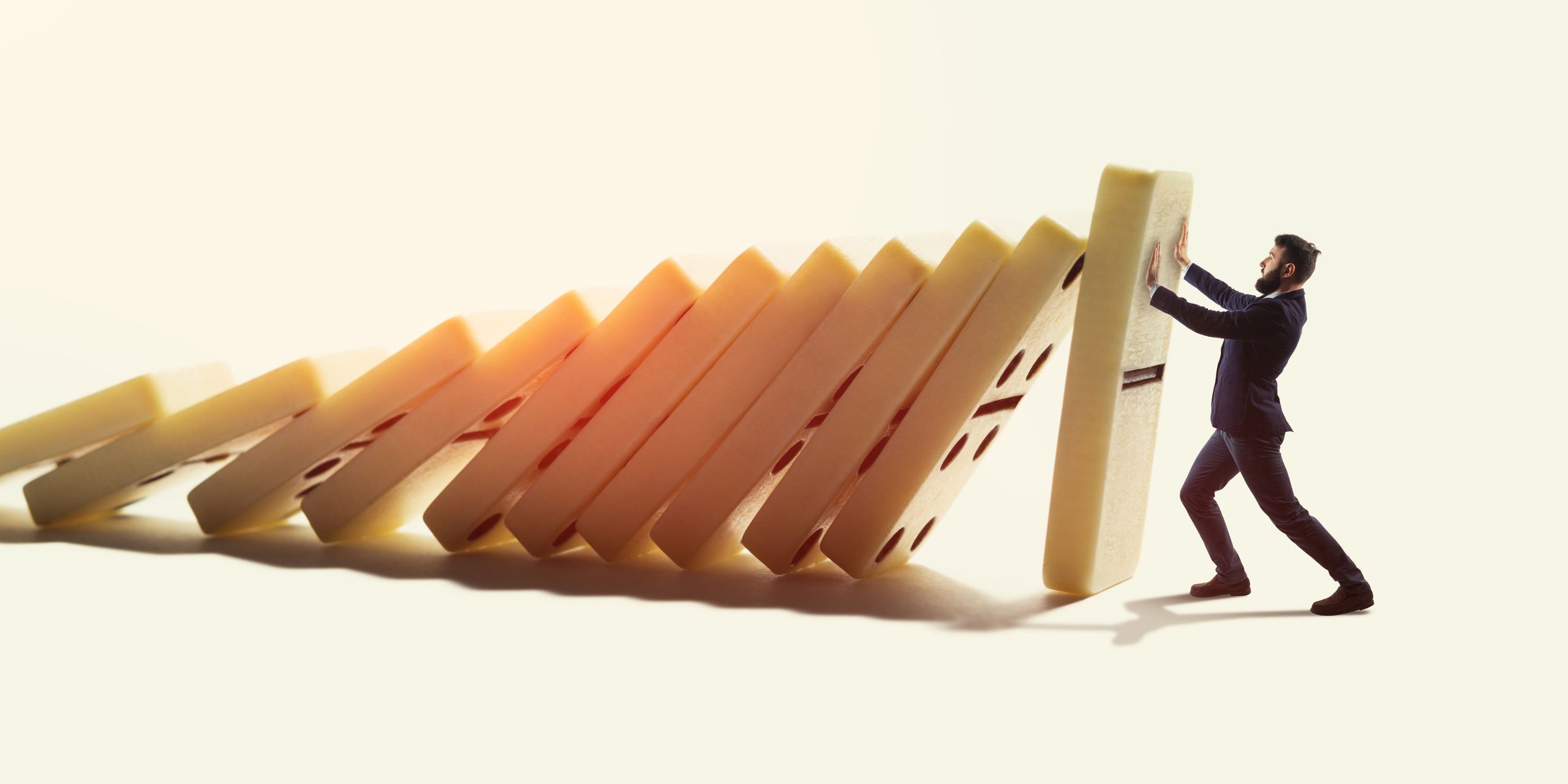 A man stopping a line of falling dominoes, representing the need to prevent issues from escalating in relationships