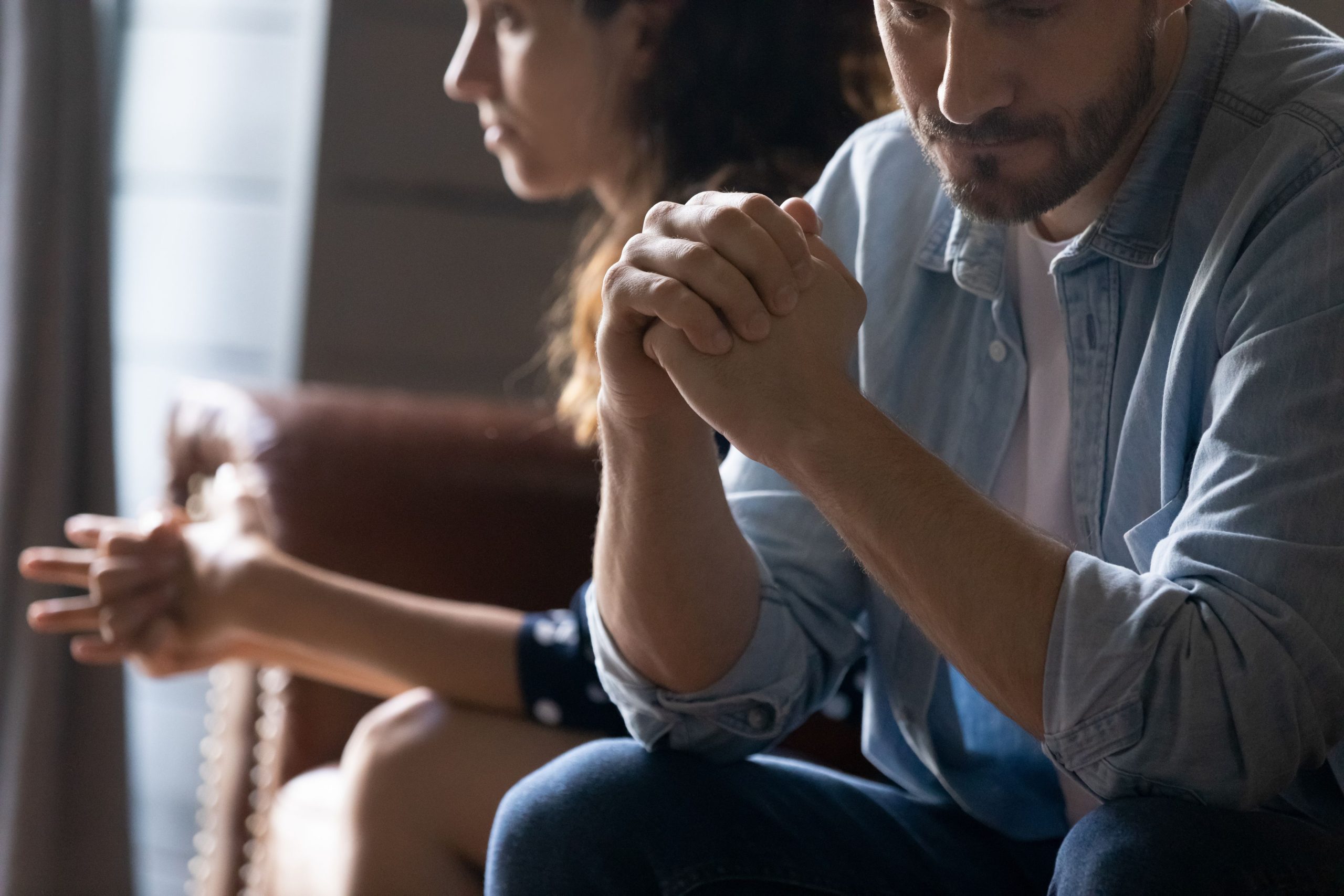 A couple sitting apart, appearing deep in thought after a conflict, symbolizing a moment of tension in their relationship.