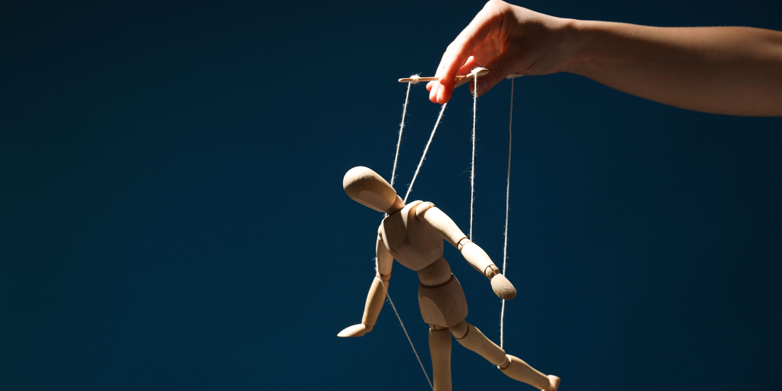 A hand controlling a marionette puppet, symbolizing manipulation and control in a relationship.